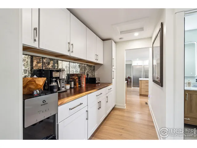 a hallway with white cabinets and wooden floor