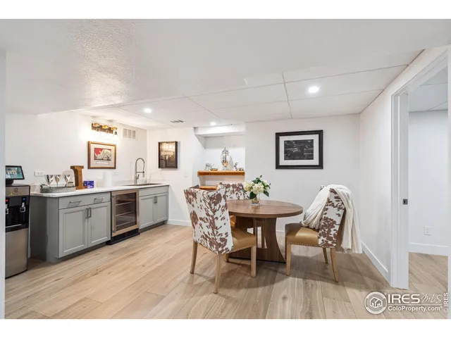 a open kitchen with stainless steel appliances kitchen island granite countertop a dining table chairs and a refrigerator