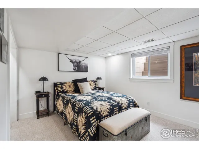 a bedroom with a bed a wall painting and a window