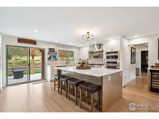 a open kitchen with stainless steel appliances granite countertop a refrigerator a stove a sink dishwasher with chairs dining table and chairs with wooden floor