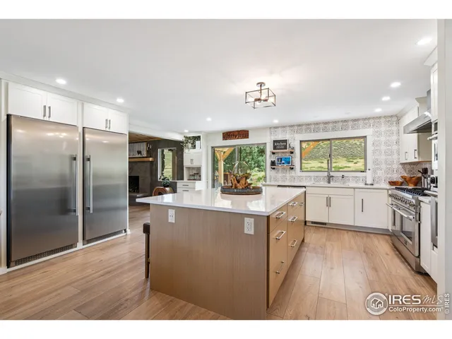 a kitchen with stainless steel appliances granite countertop a refrigerator a sink dishwasher a oven with white cabinets and wooden floor