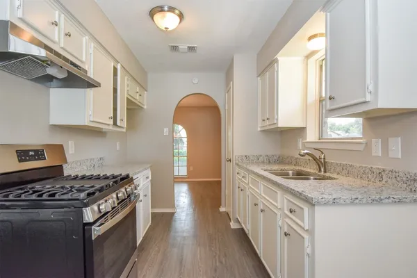a kitchen with granite countertop stainless steel appliances a stove a sink a window and cabinets