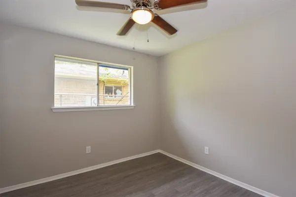 a view of an empty room with window and wooden floor