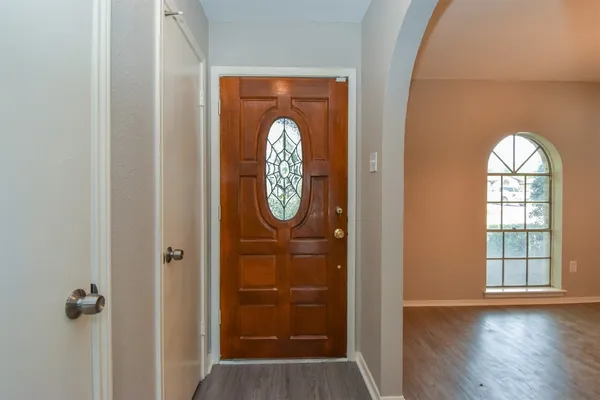 an empty room with wooden floor mirror and windows