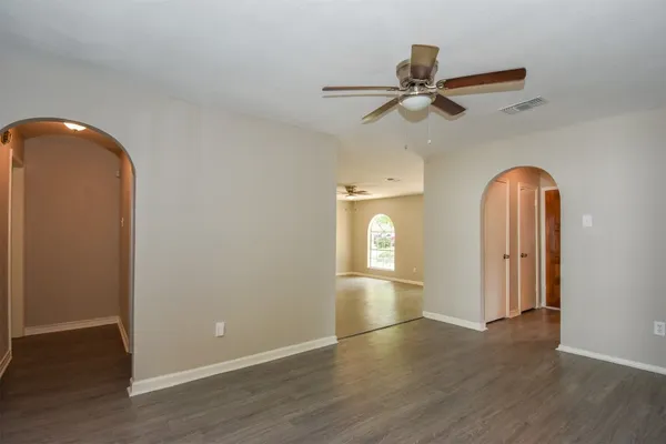 an empty room with wooden floor closet and windows