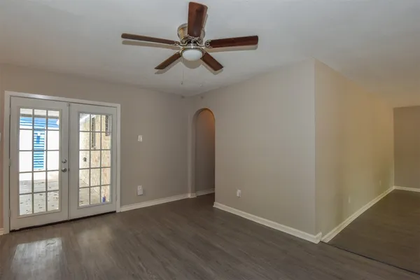 an empty room with wooden floor fan and windows