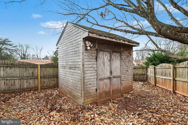 a view of a wooden house with a large tree and wooden fence