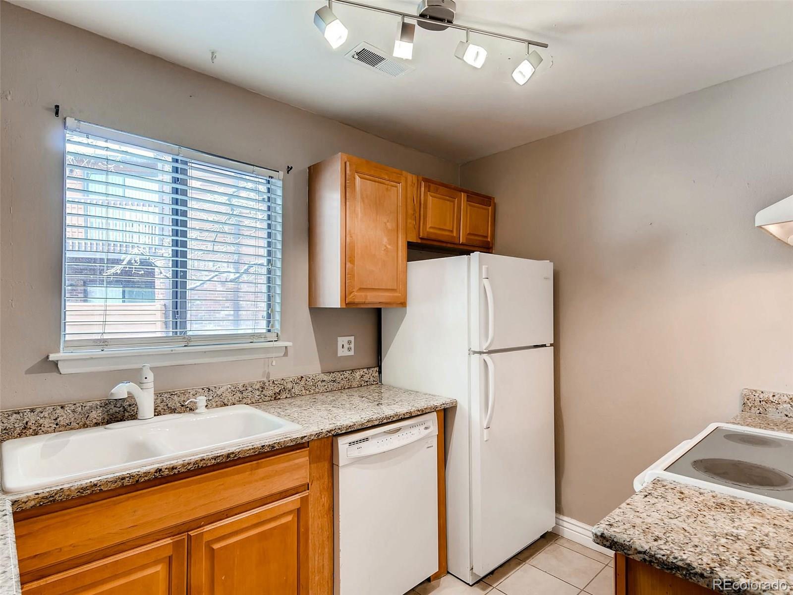 2263 South Buckley Road, Unit 101 Aurora, CO 80013 - Photo 4 of 11 a bathroom with a granite countertop sink and a refrigerator