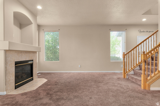 3053 Sage Loop, Unit B1 Lehi, UT 84043 - Photo 4 of 25 Living space featuring a tile-surround fireplace with hearth, a built-in arched alcove, recessed lighting, and two windows with blinds
