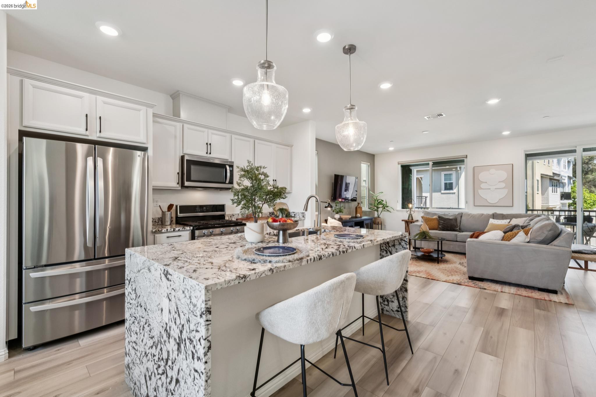 24157 Amaranth Loop Hayward, CA 94541 - Photo 25 of 63 Open-concept living space featuring a gourmet kitchen with a waterfall island, stainless steel appliances, and white shaker cabinetry