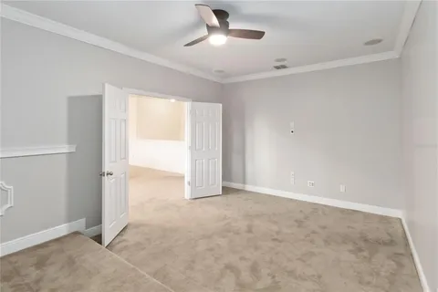 a view of an empty room and chandelier fan