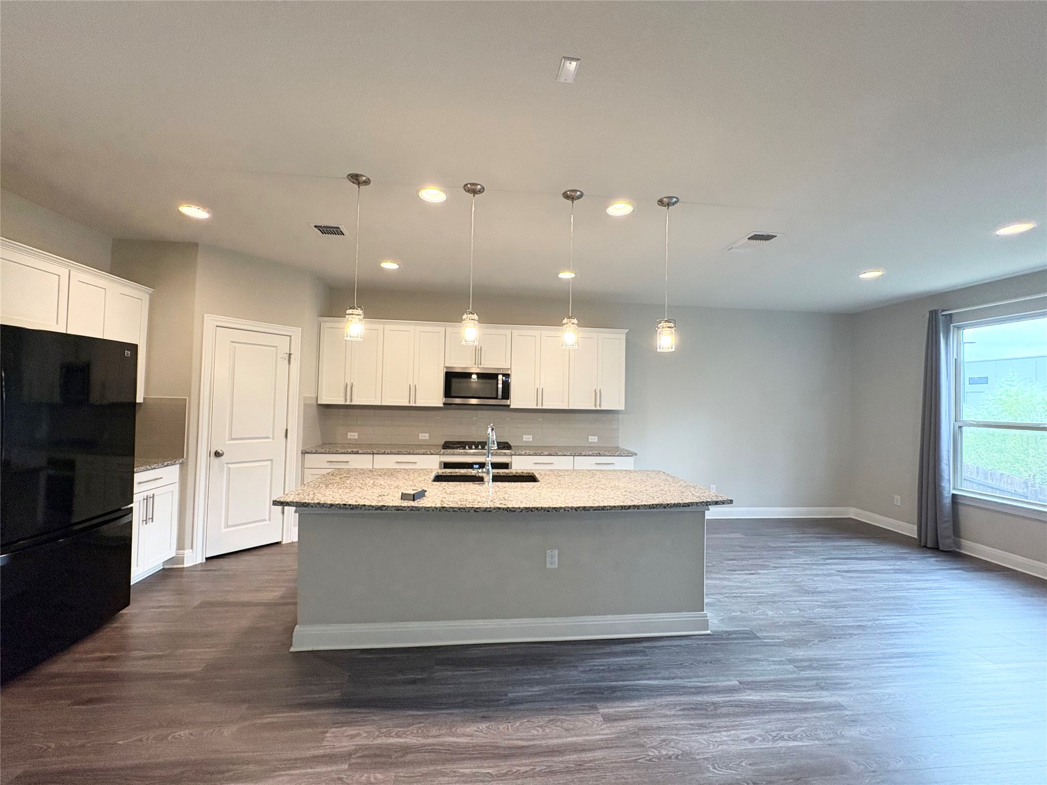 16103 Windroot Street Austin, TX 78728 - Photo 8 of 32 Gleaming stone countertops and a spacious central island anchor this open-concept kitchen space.