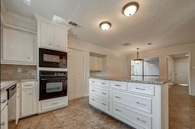 a kitchen with granite countertop white cabinets and stainless steel appliances