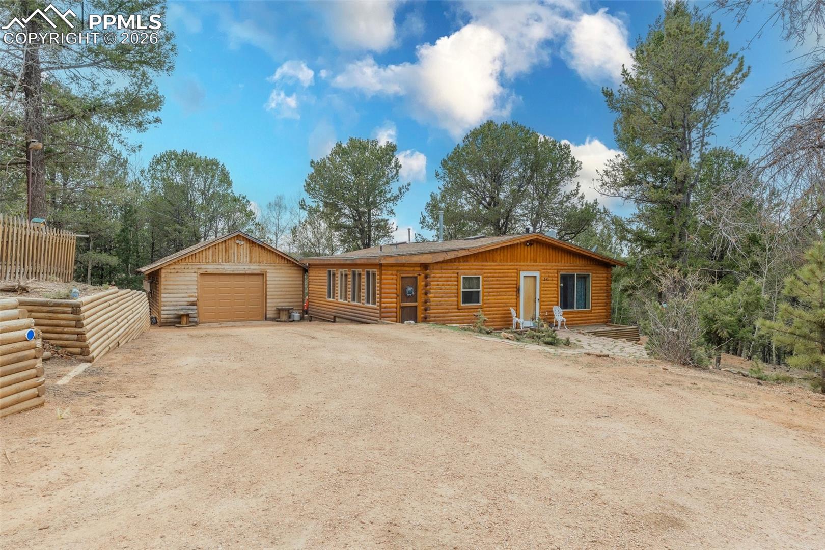 847 Timber Ridge Road Divide, CO 80814 - Photo 1 of 41 Log cabin style residence featuring a detached garage, natural wood siding, multiple windows, a front entry door, and a retaining wall
