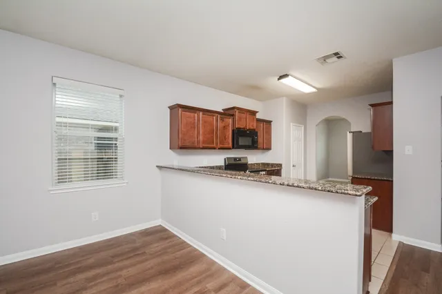 a kitchen with granite countertop a sink cabinets and wooden floor