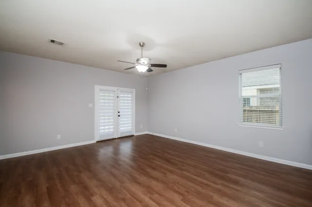 a view of an empty room with wooden floor and a window