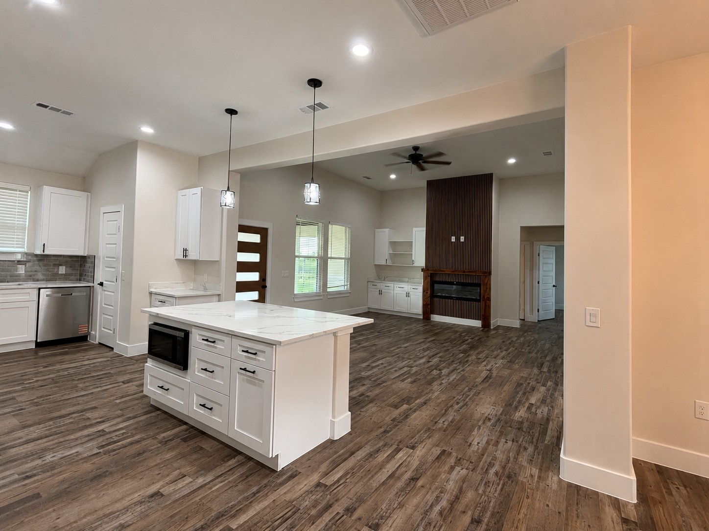 488 County Road 468 Elgin, TX 78621 - Photo 5 of 12 A contemporary open-concept space features a central kitchen island and a fireplace with a decorative wood panel.