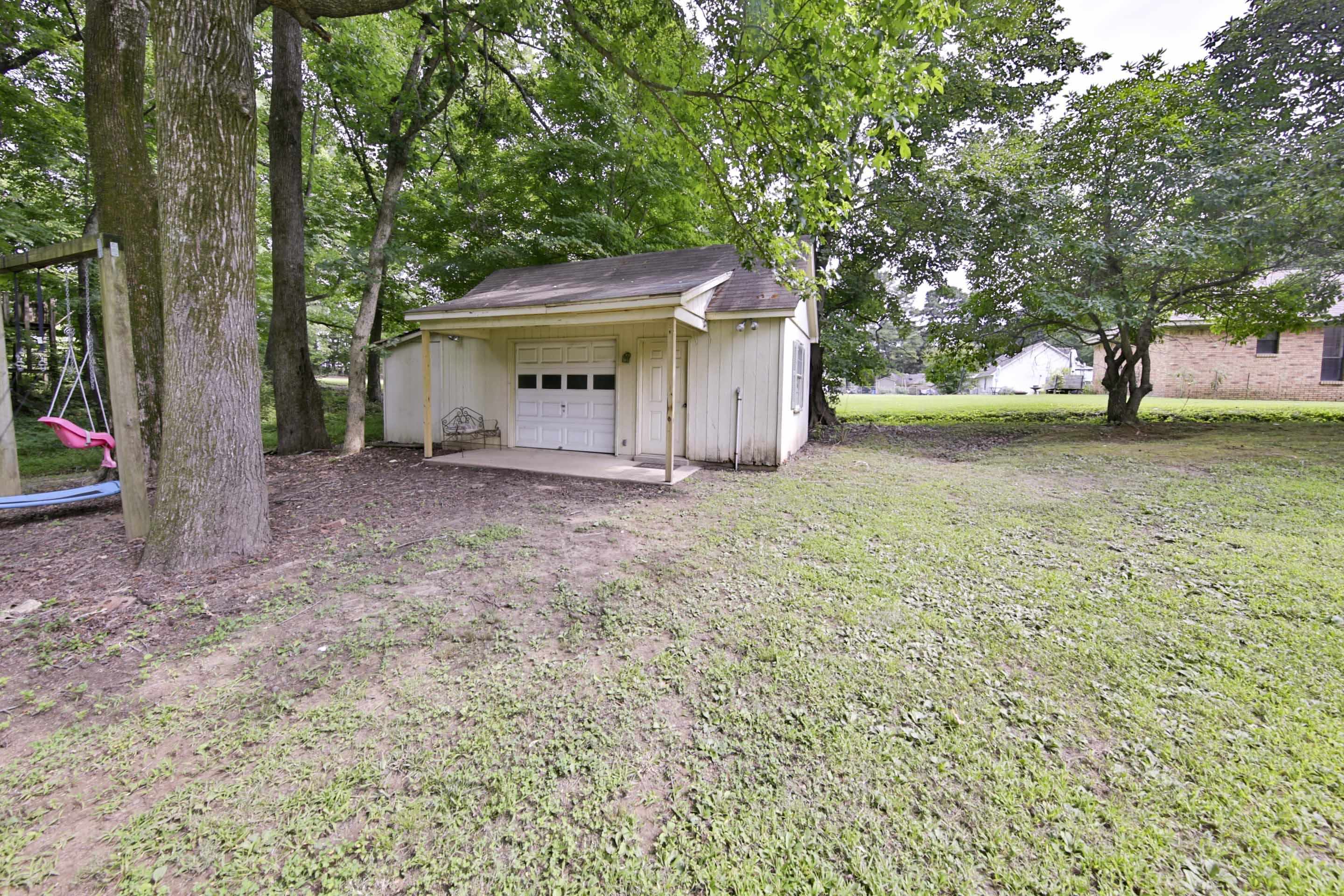 104 Miller Road Covington, TN 38019 - Photo 7 of 25 Detached garage featuring a roll-up door, covered concrete pad, and vertical siding
