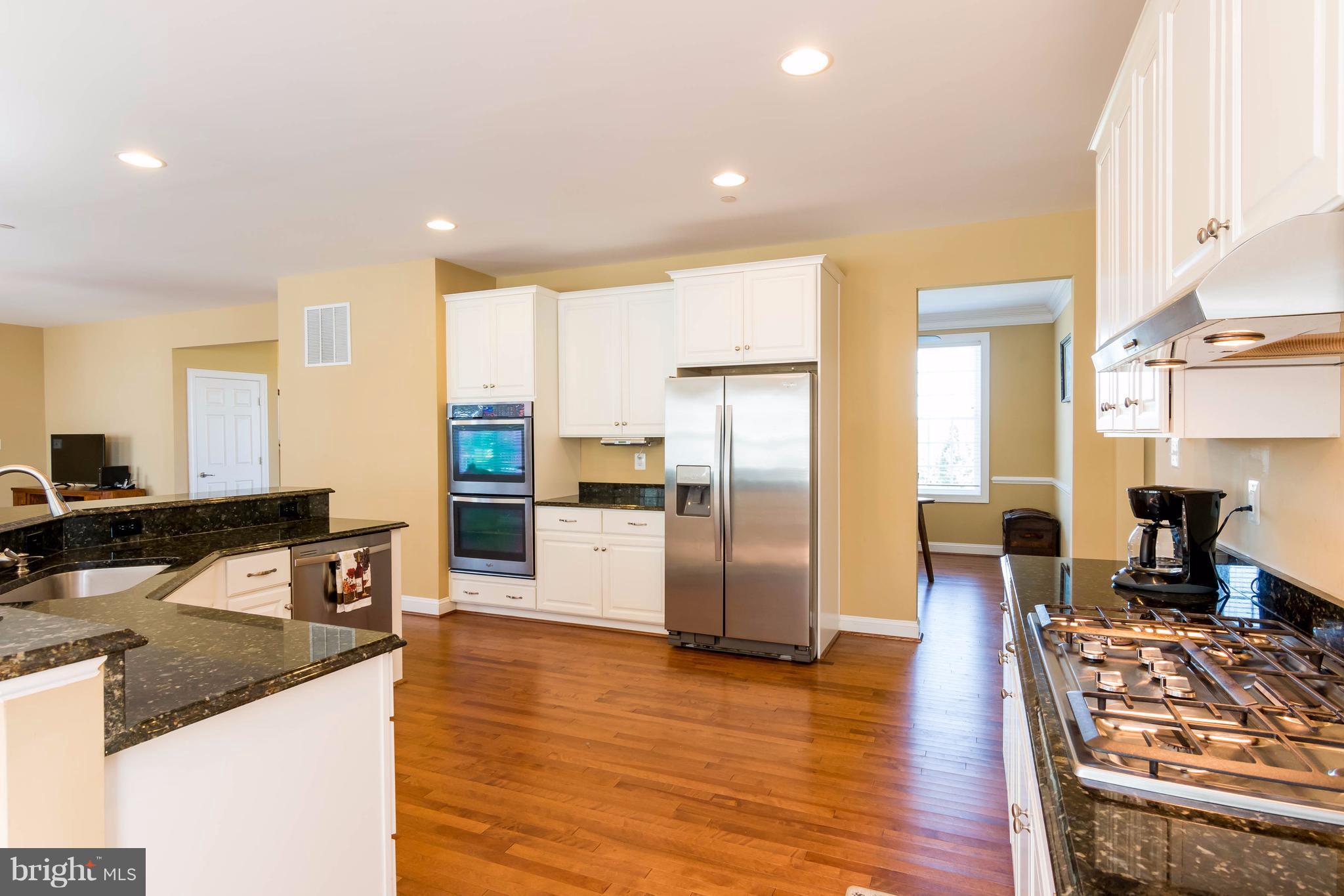 3333 Whispering Highland Road Finksburg, MD 21048 - Photo 10 of 30 a kitchen with stainless steel appliances granite countertop a refrigerator a stove top oven a sink dishwasher and chairs with wooden floor