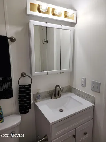 a en suite bathroom with a granite countertop sink and a mirror