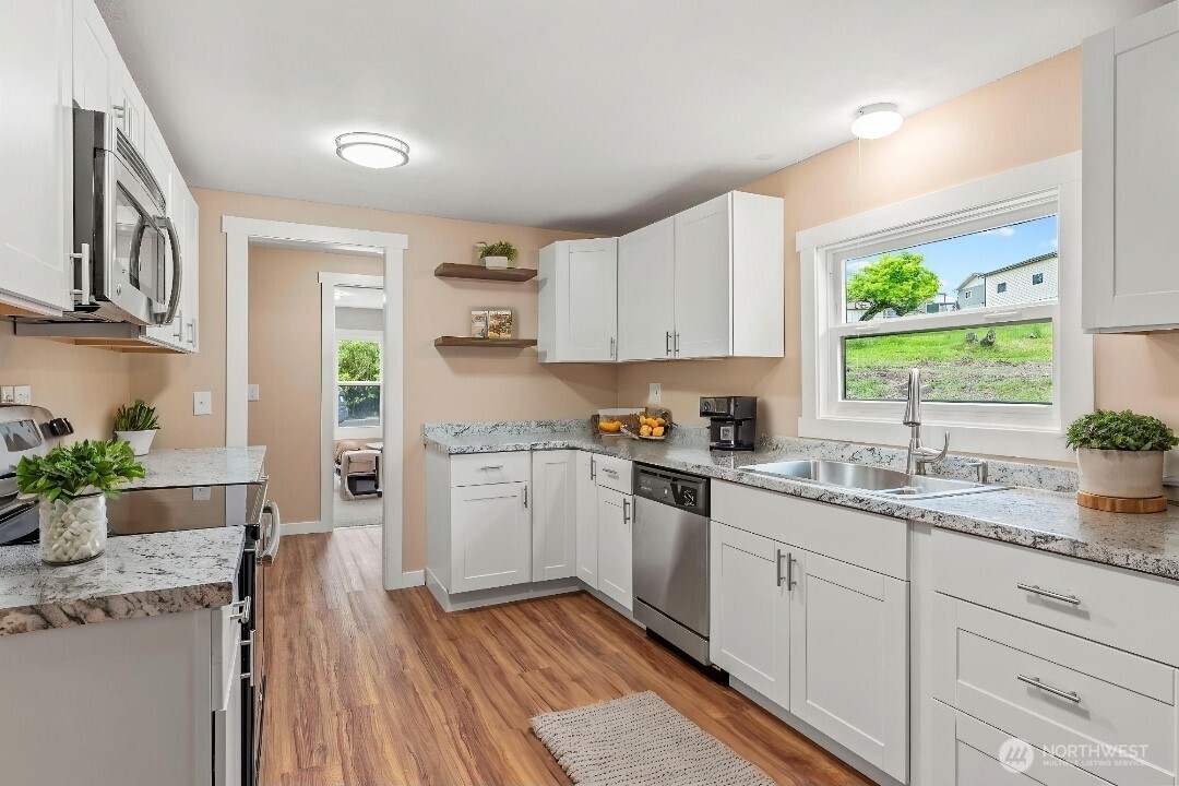 2914 Columbia Heights Road Longview, WA 98632 - Photo 16 of 29 a kitchen with a sink dishwasher stove and white cabinets with wooden floor