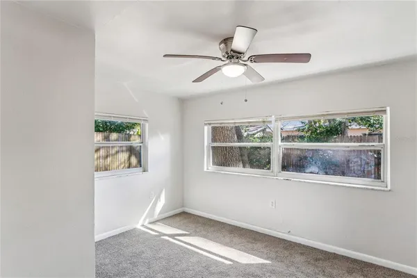 an empty room with wooden floor fan and windows