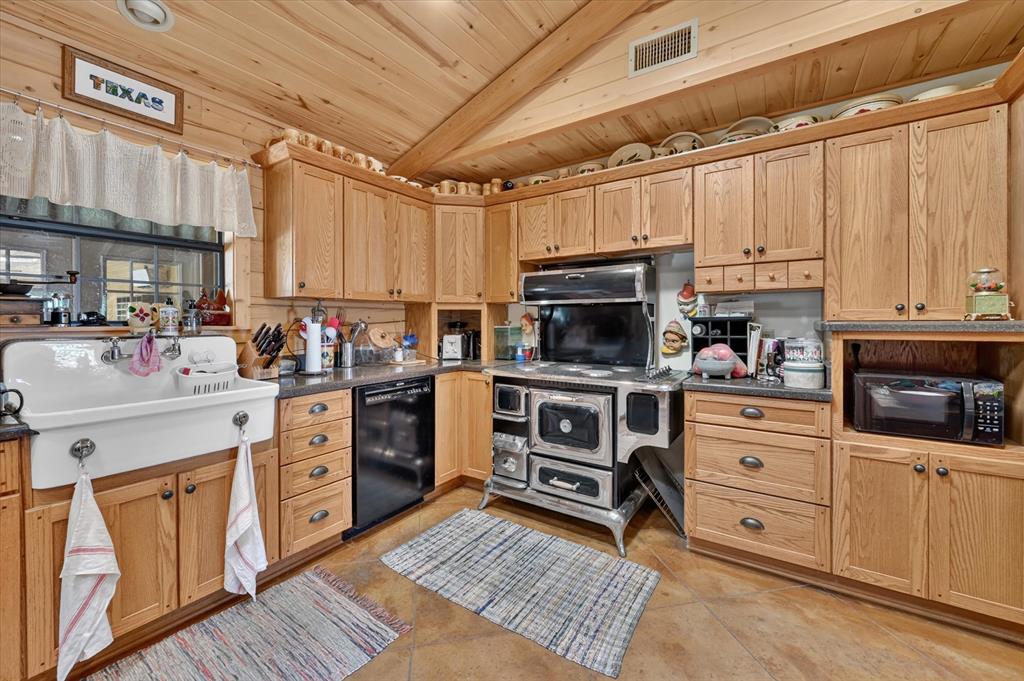 1623 3 Skillet Road Springtown, TX 76082 - Photo 17 of 40 Wood-paneled ceilings, extensive wood cabinetry, farmhouse sink, black dishwasher, and built-in microwave