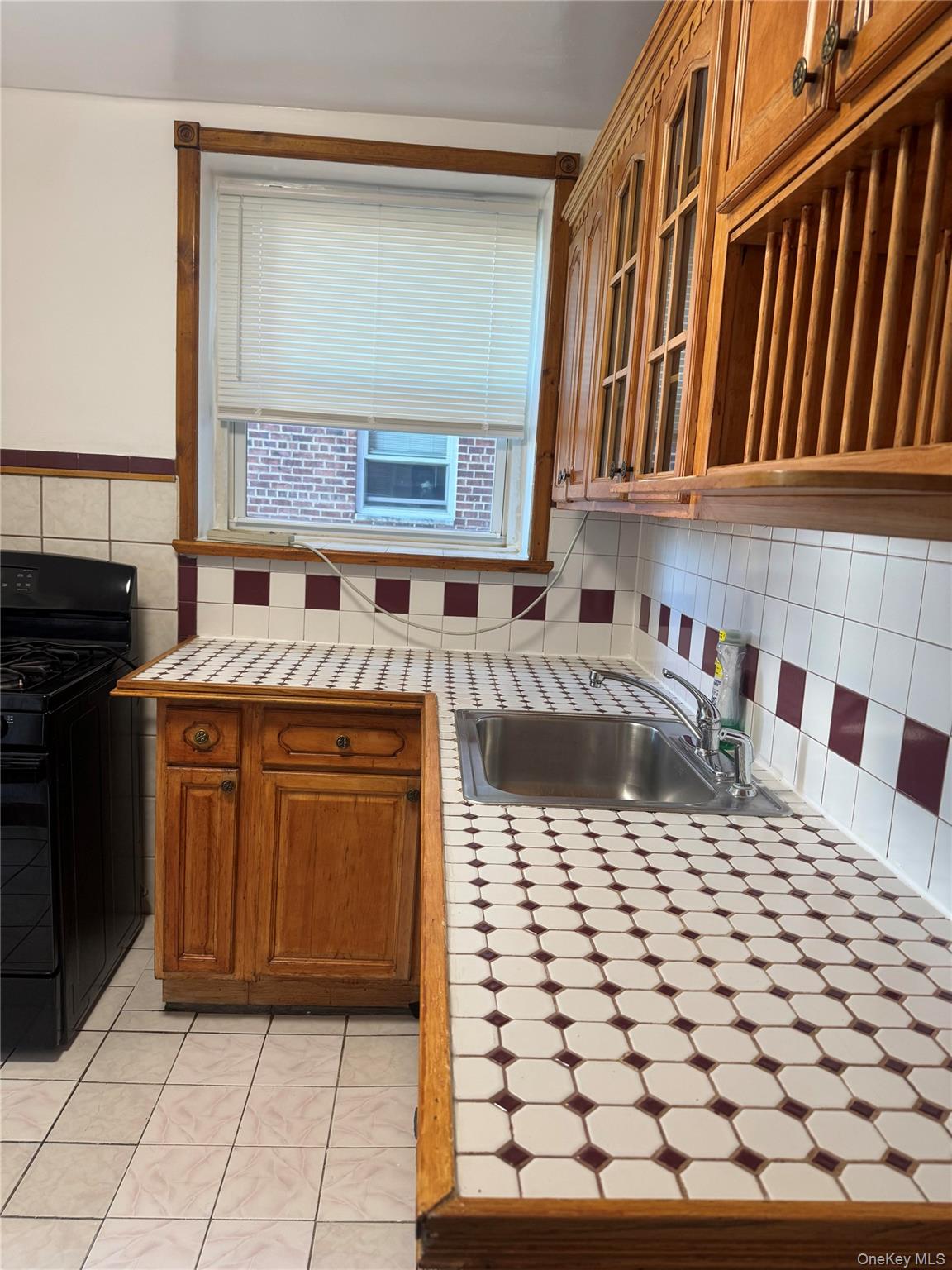 84-50 169th Street, Unit 306 Queens, NY 11432 - Photo 6 of 9 a kitchen with a stove a sink and a microwave