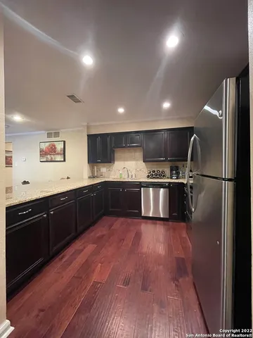 a large kitchen with wooden floors stainless steel appliances and a window