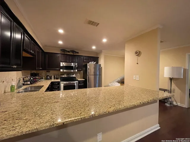 a kitchen with stainless steel appliances granite countertop a sink a stove and a refrigerator