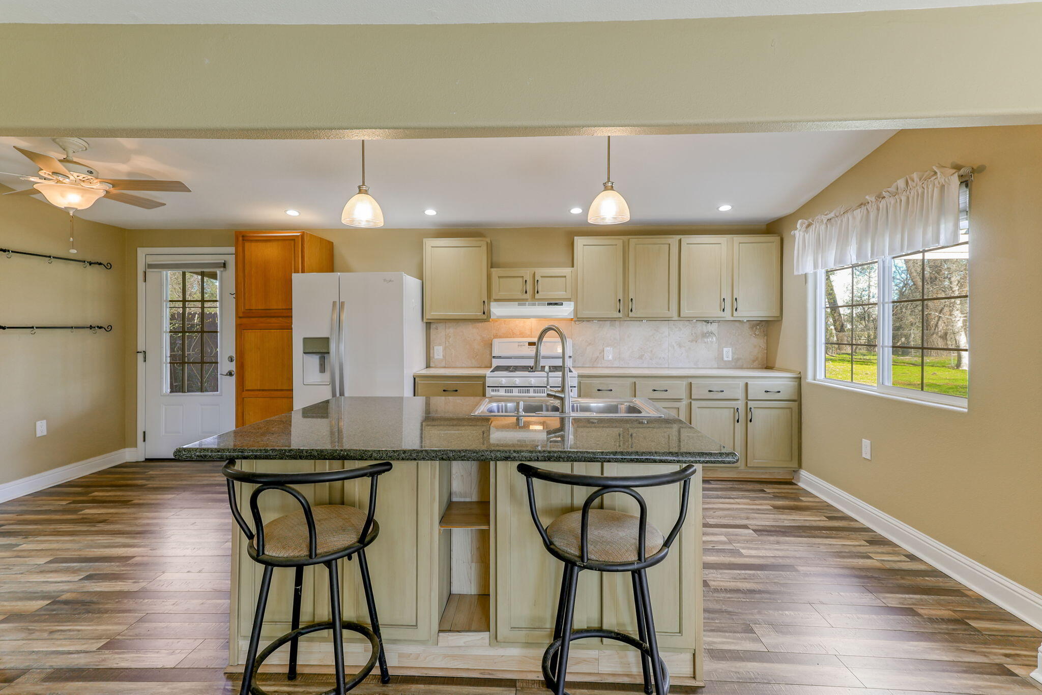 5082 Happy Valley Road Anderson, CA 96007 - Photo 47 of 66 a kitchen with stainless steel appliances kitchen island granite countertop a table chairs in it and wooden floors