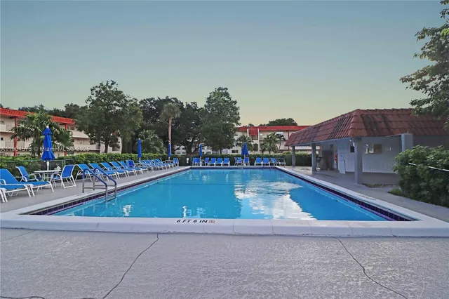 a view of swimming pool with outdoor seating and trees in the background