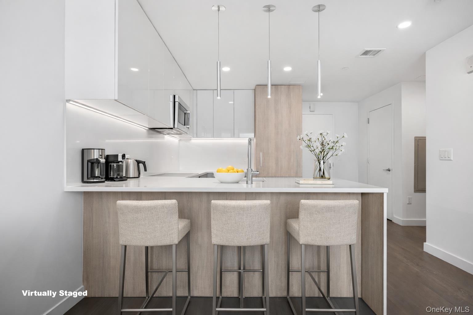 131-05 40 Road, Unit 18H Queens, NY 11354 - Photo 8 of 14 a kitchen with kitchen island stainless steel appliances a table chairs in it and wooden floor