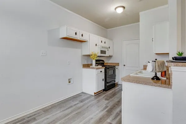 a kitchen with cabinets and wooden floor