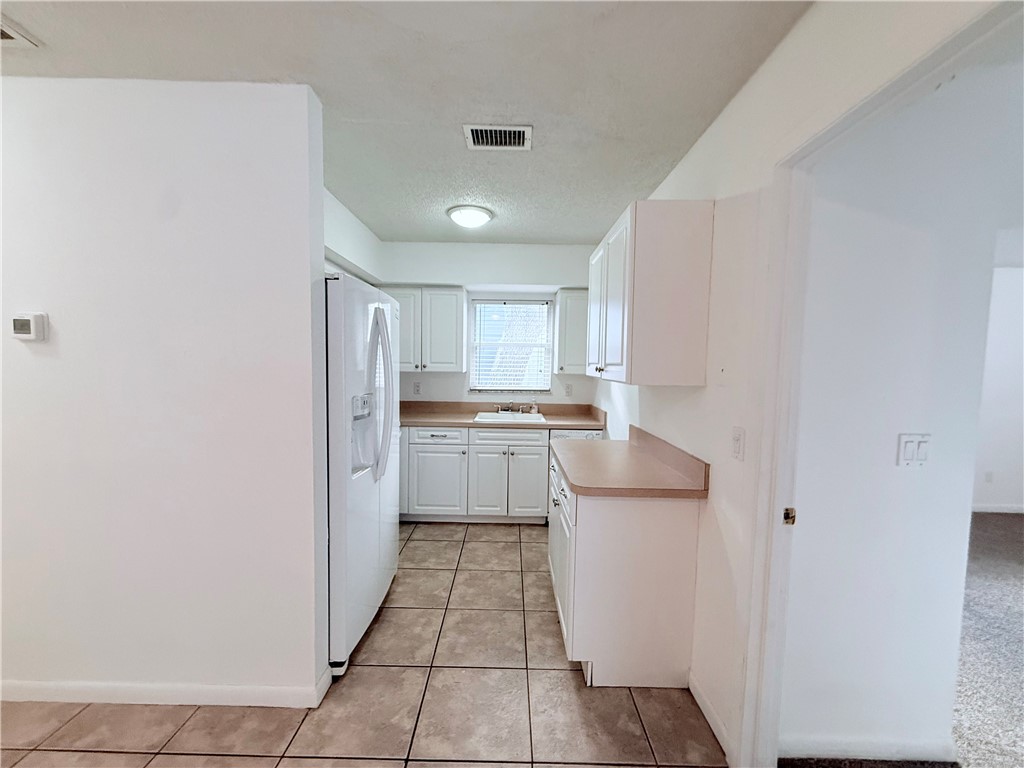 224 Georgia Street Vero Beach, FL 32962 - Photo 10 of 23 a kitchen with a refrigerator and white cabinets