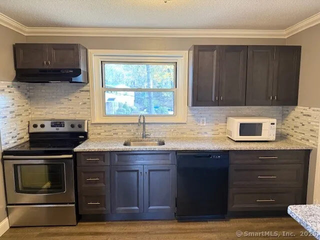 a kitchen with granite countertop a stove a sink and a microwave