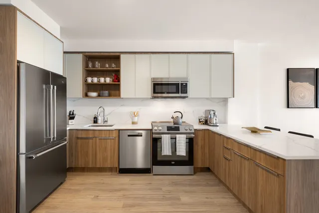 a kitchen with stainless steel appliances granite countertop a refrigerator a sink a stove a microwave and wooden cabinets