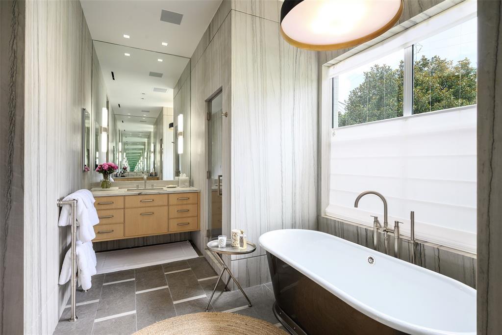 3511 Springbrook Street Dallas, TX 75205 - Photo 30 of 38 Contemporary bathroom featuring a freestanding soaking tub, a floating dual vanity with integrated sinks, and full-height wall paneling