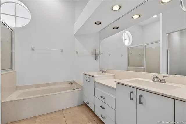 a bathroom with a tub a sink double vanity and a mirror