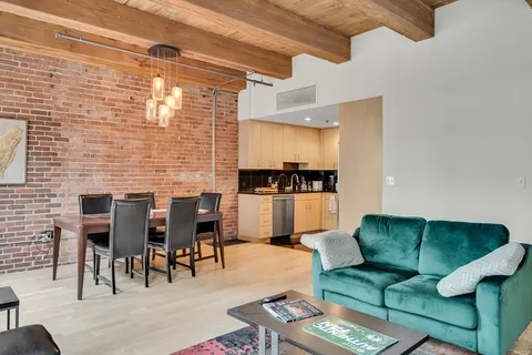 a living room with couches and kitchen view with wooden floor