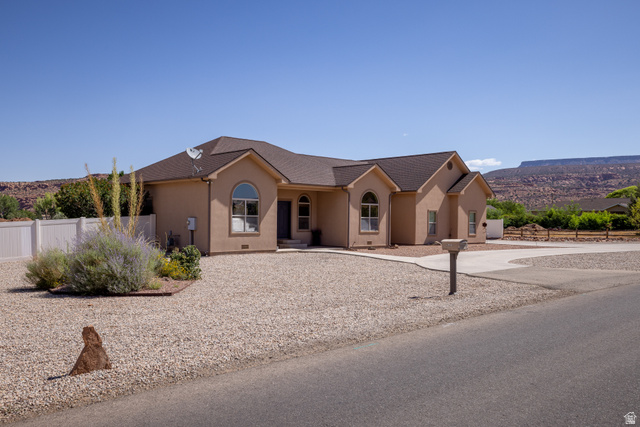 4635 East Sunny Acres Lane Moab, UT 84532 - Photo 17 of 56 Stucco exterior with arched windows, a multi-gabled roof, and a gravel front yard