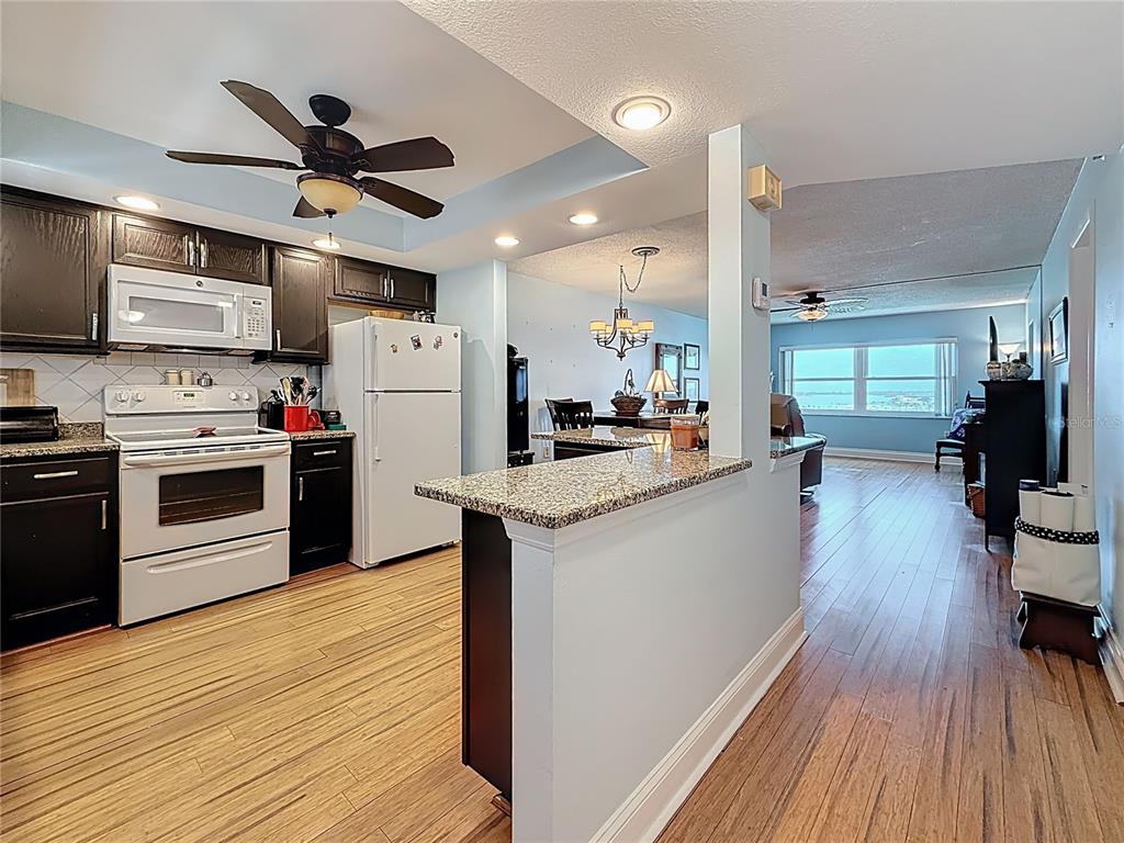 4725 Cove Circle, Unit 908 St. Petersburg, FL 33708 - Photo 13 of 61 a kitchen with stainless steel appliances a stove top oven a sink dishwasher and a refrigerator with wooden floor