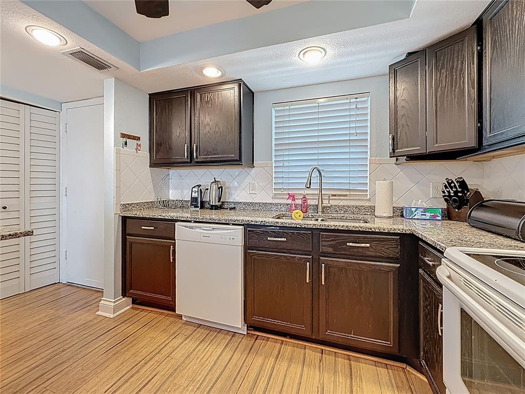 4725 Cove Circle, Unit 908 St. Petersburg, FL 33708 - Photo 15 of 61 a kitchen with granite countertop wooden cabinets stainless steel appliances a sink and a window