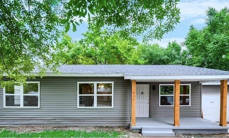 a view of front of a house with plants and a tree