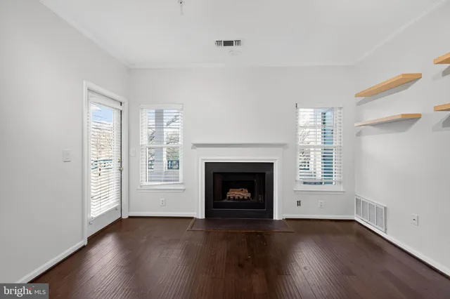 an empty room with wooden floor fireplace and windows