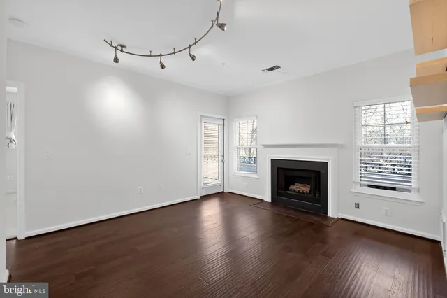 a view of a livingroom with wooden floor a fireplace and windows