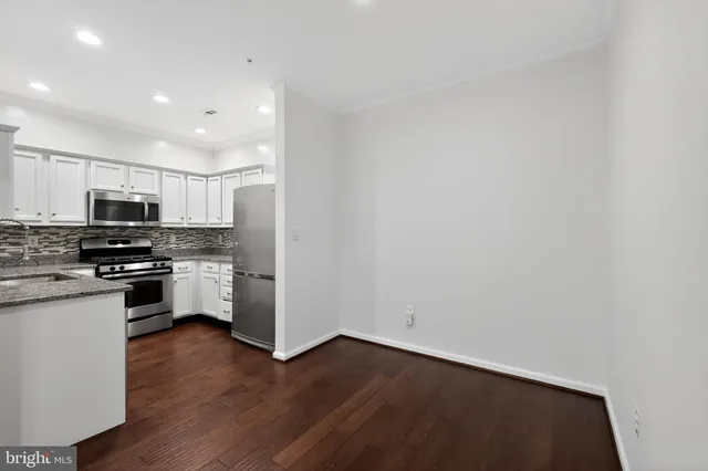 a kitchen with granite countertop white cabinets and stainless steel appliances