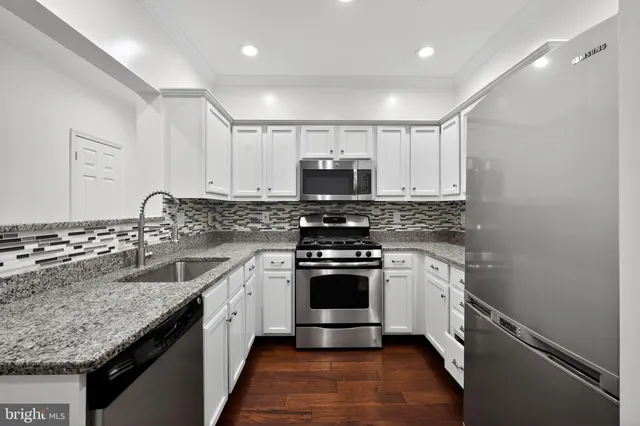 a kitchen with granite countertop a sink stove and microwave