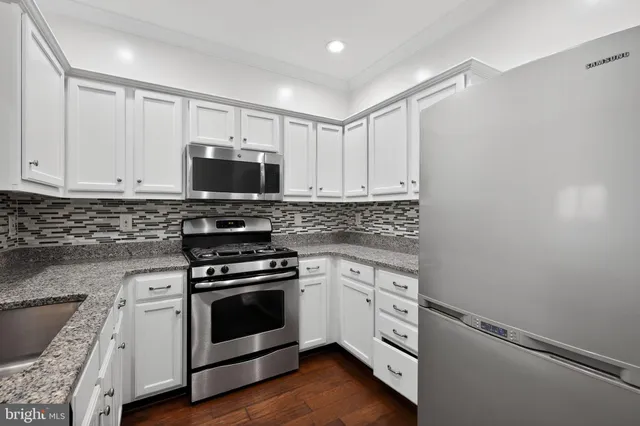 a kitchen with cabinets stainless steel appliances and wooden floor