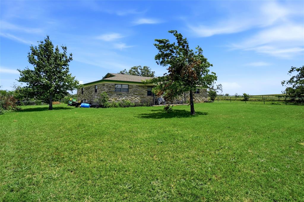 2186 Gilliland Road Springtown, TX 76082 - Photo 14 of 25 Stone exterior residence with a composition shingle roof, surrounded by expansive green lawn
